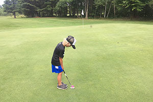 An image of a boy golfing.