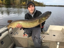 A picture of a man in a boat holding a fish.