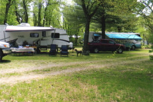 An image of a camp spot with a trailer and vehicles.