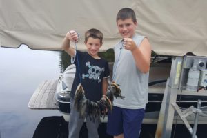 An image of 2 boys holding a stringer of fish.