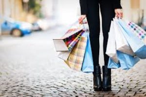 An image of the lower half of a woman, holding several shopping bags.