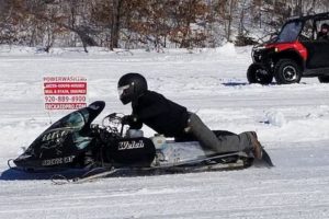 A picture of a man riding a snow mobile.