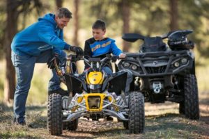 An image of a man and boy with their ATV's.