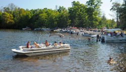 A picture of several boats and people lining the shores of the water.