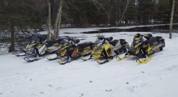 A picture of 4 snow mobiles set in front of the water.