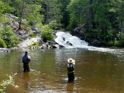 A picture of 2 people fly fishing in the water.