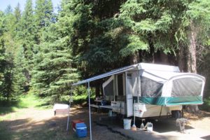 An image of a camp trailer set up among trees.