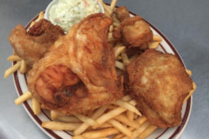 An image of a dinner plate with fried chicken, french fries and cole slaw.