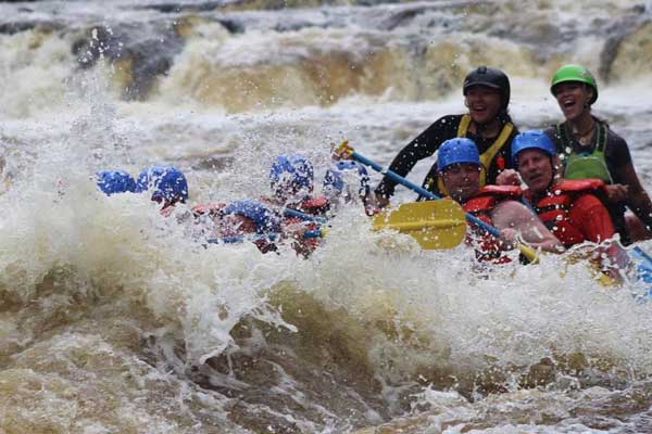 An image of a group of people white water rafting, with water splashing up.