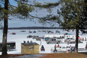 An image of several vehicles and people ice fishing.